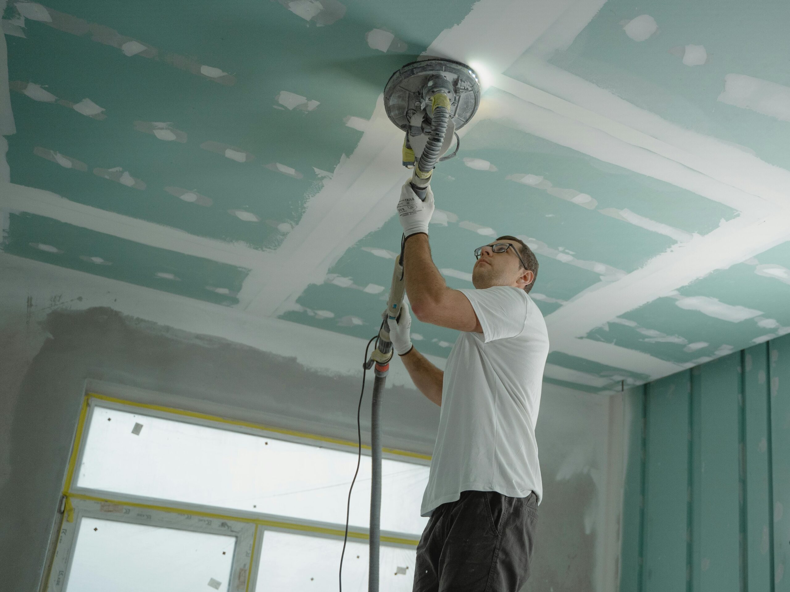 pexels photo 6474343 6474343 A professional worker sanding the ceiling during a home renovation project. Indoor construction setting.